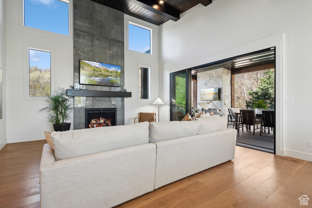 Living room featuring a towering ceiling, a fireplace, healthy amount of natural light, baseboards, and hardwood / wood-style floors