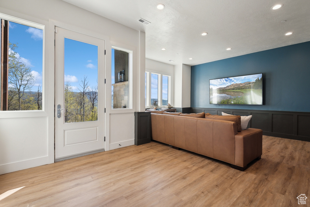 Living area featuring light wood finished floors, recessed lighting, and wainscoting