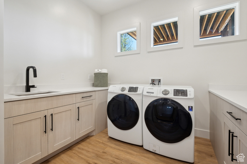 Laundry room featuring independent washer and dryer, light wood finished floors, and cabinet space