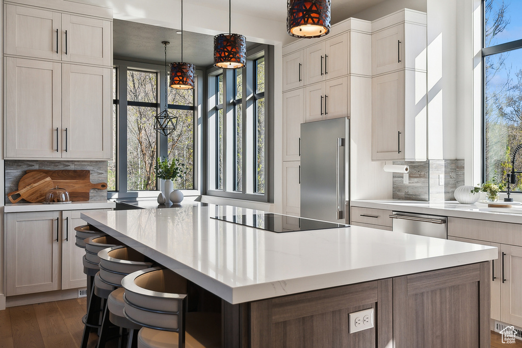 Kitchen with stainless steel appliances, light countertops, plenty of natural light, and decorative backsplash