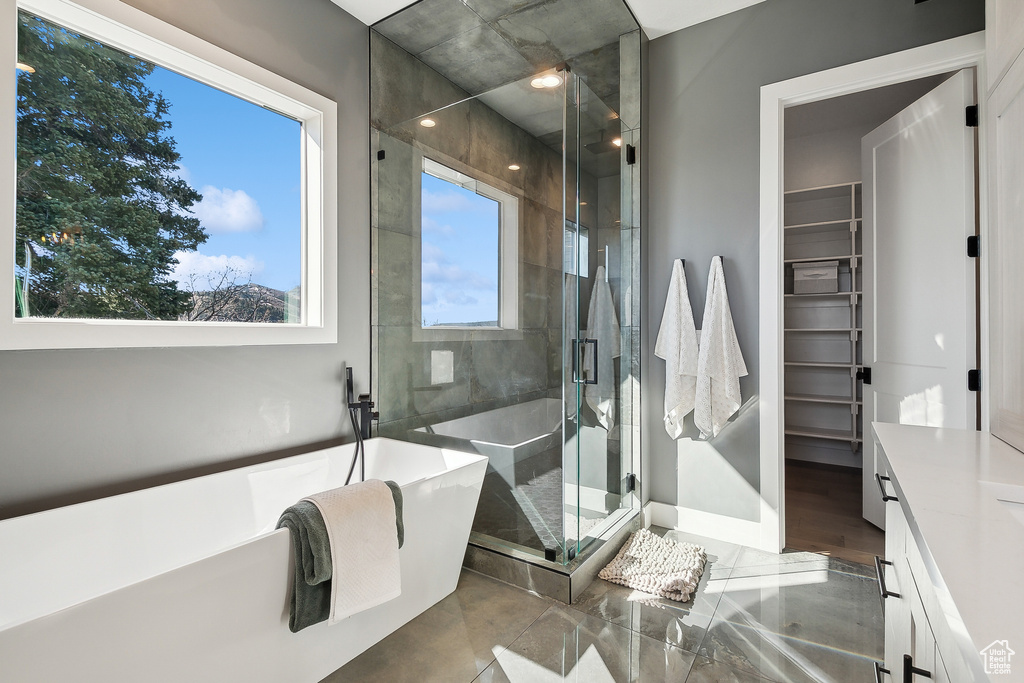 Full bathroom with a stall shower, a freestanding bath, a spacious closet, and baseboards