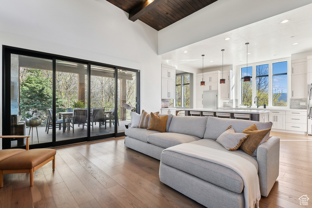 Living area featuring high vaulted ceiling, healthy amount of natural light, beamed ceiling, light wood-style flooring, and wooden ceiling