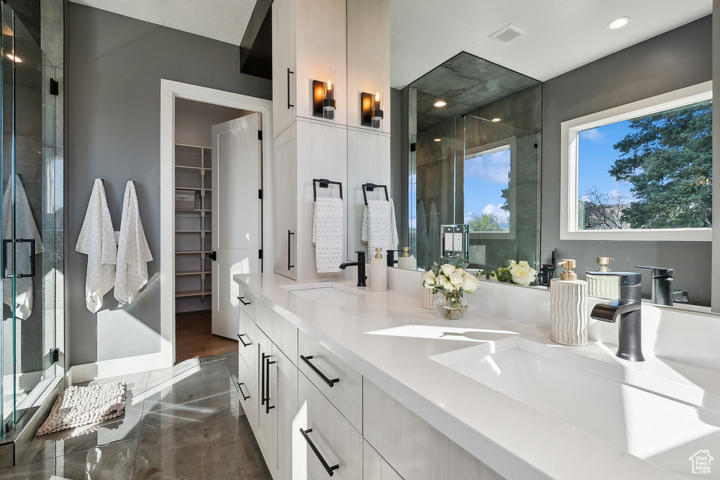 Full bath featuring a shower stall, recessed lighting, double vanity, and a walk in closet