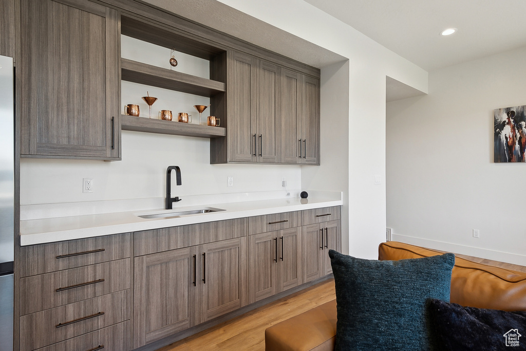 Kitchen featuring a sink, light wood-style flooring, light countertops, open shelves, and recessed lighting