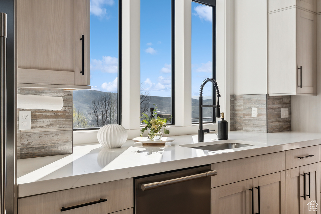 Kitchen with dishwasher, backsplash, a sink, light countertops, and a mountain view