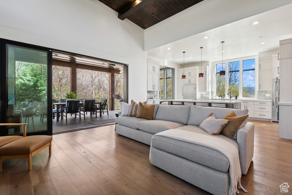 Living room featuring hardwood / wood-style floors, beam ceiling, high vaulted ceiling, wooden ceiling, and recessed lighting