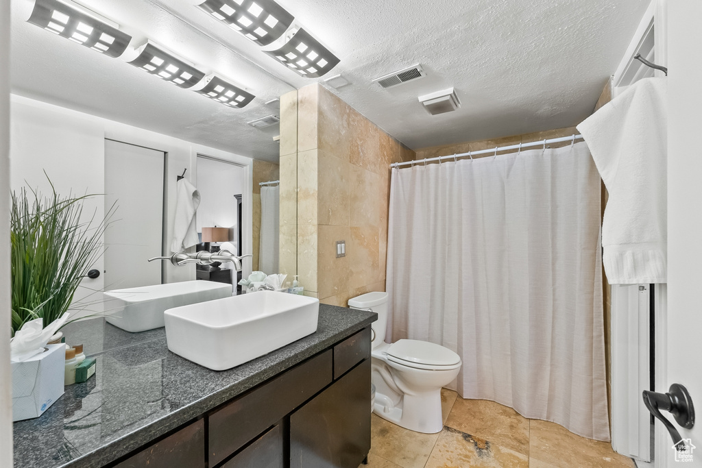 Bathroom with a textured ceiling, oversized vanity, toilet, and tile floors