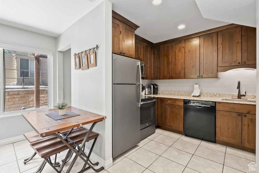 Kitchen featuring range with electric cooktop, stainless steel refrigerator, sink, dishwasher, and light tile floors