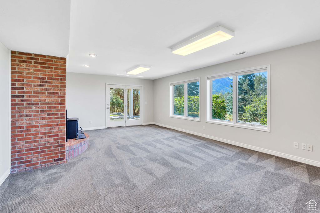 Unfurnished living room featuring brick wall and carpet