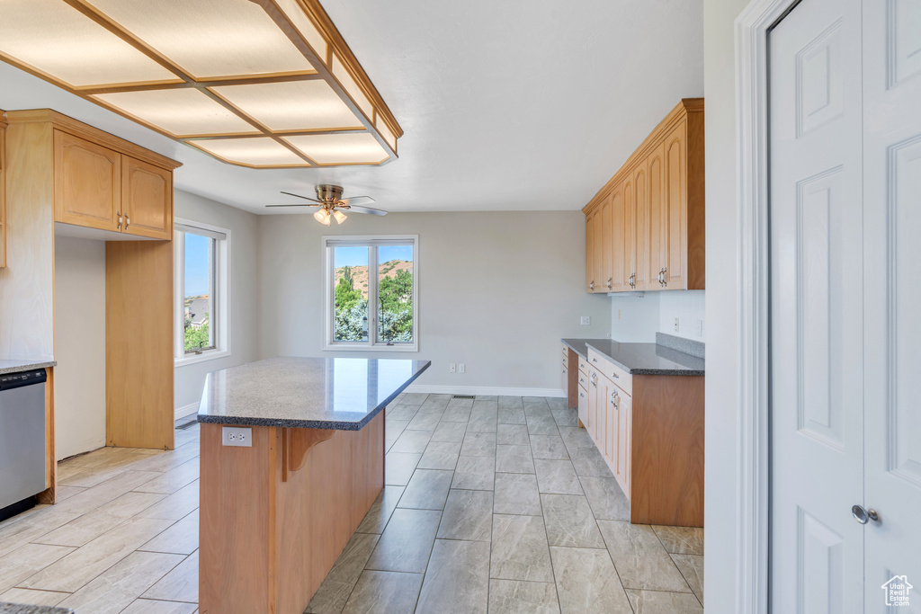 Kitchen with a breakfast bar area, ceiling fan, light tile floors, and a kitchen island