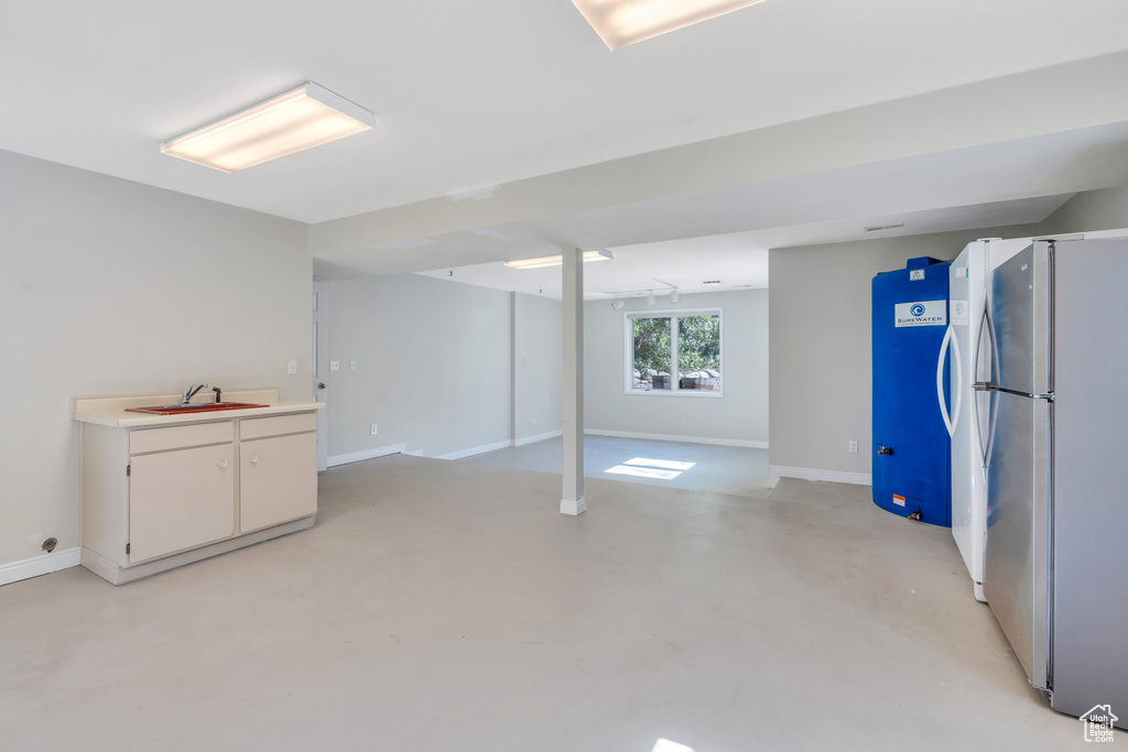 Basement featuring white refrigerator and sink