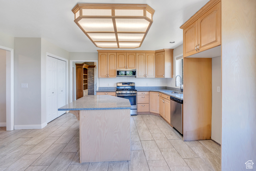 Kitchen with appliances with stainless steel finishes, a center island, sink, and light tile floors