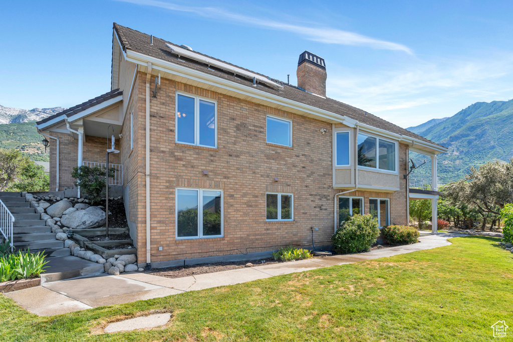 Rear view of property featuring a lawn and a mountain view