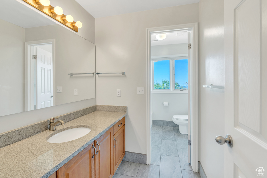 Bathroom featuring oversized vanity, toilet, and tile floors