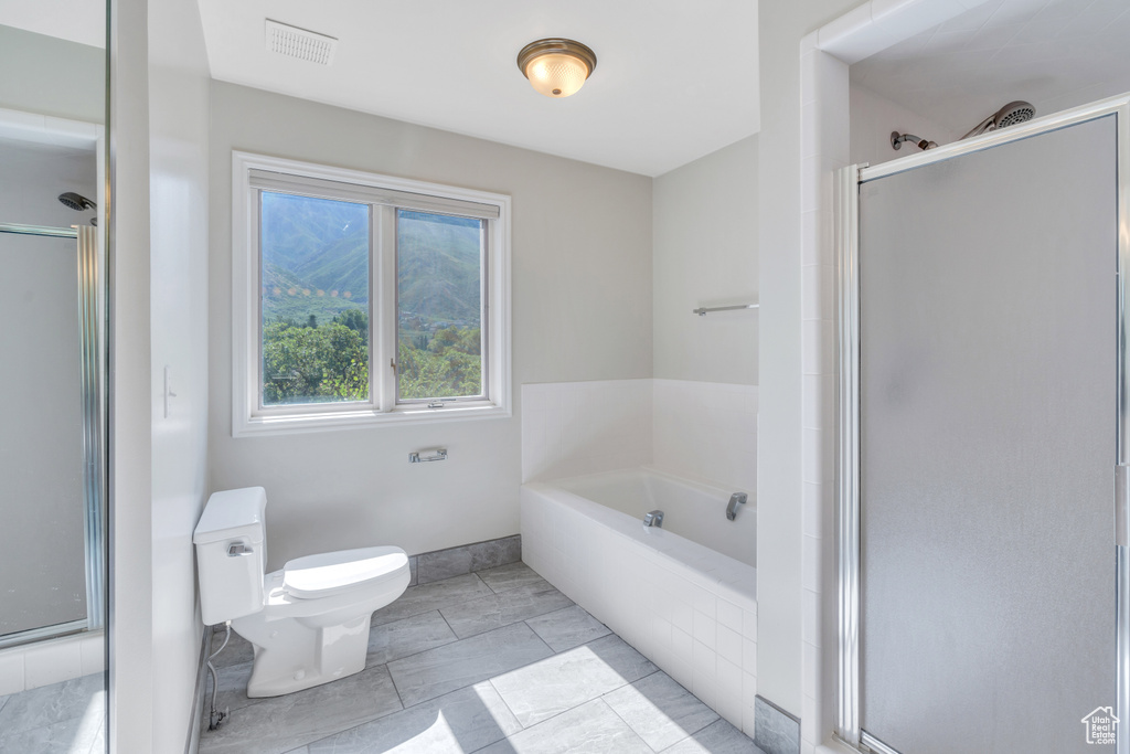 Bathroom featuring tile flooring, toilet, and plus walk in shower