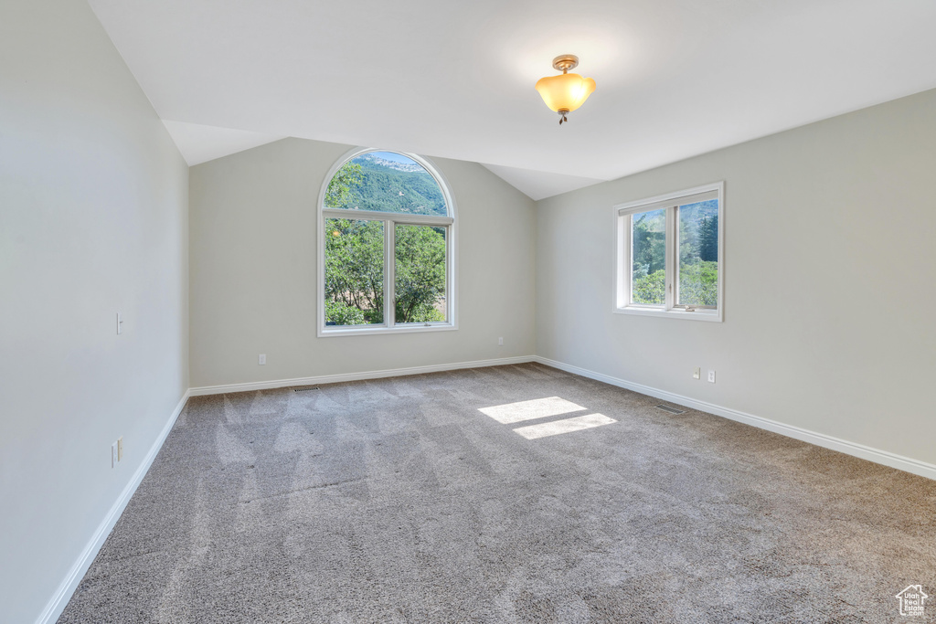 Carpeted empty room with lofted ceiling