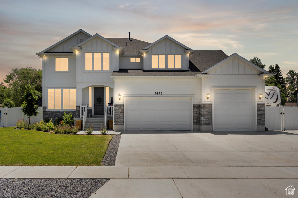 View of front of home with a garage and a yard