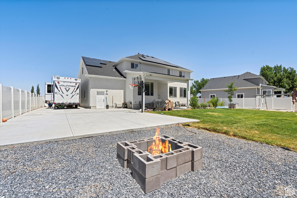 View of front of property featuring a front yard, a fire pit, a patio, and solar panels