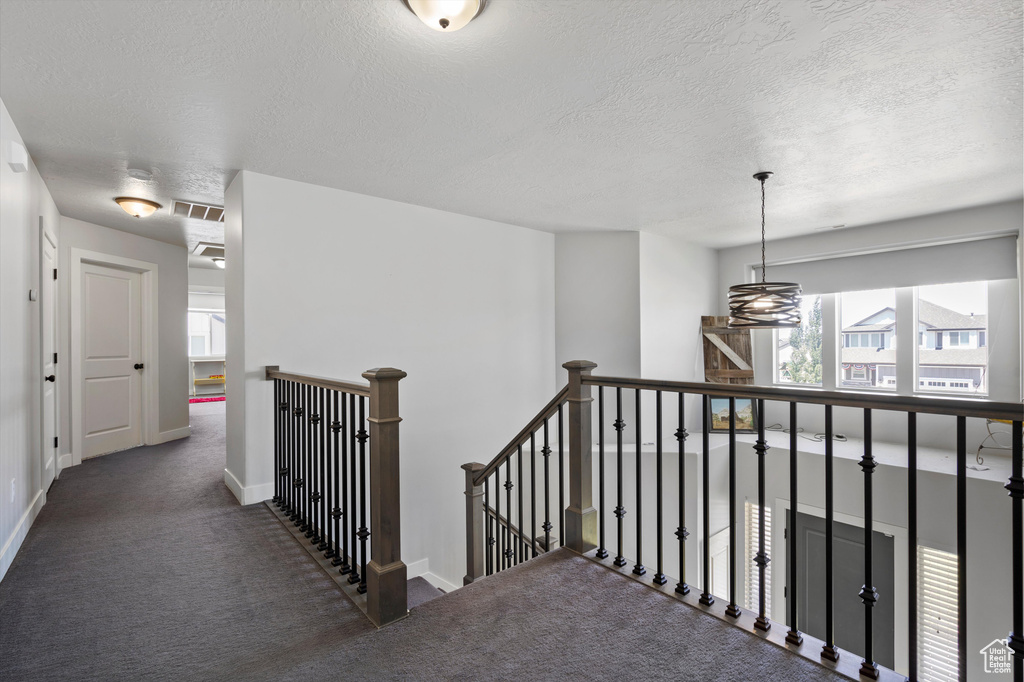 Corridor featuring dark carpet and a textured ceiling