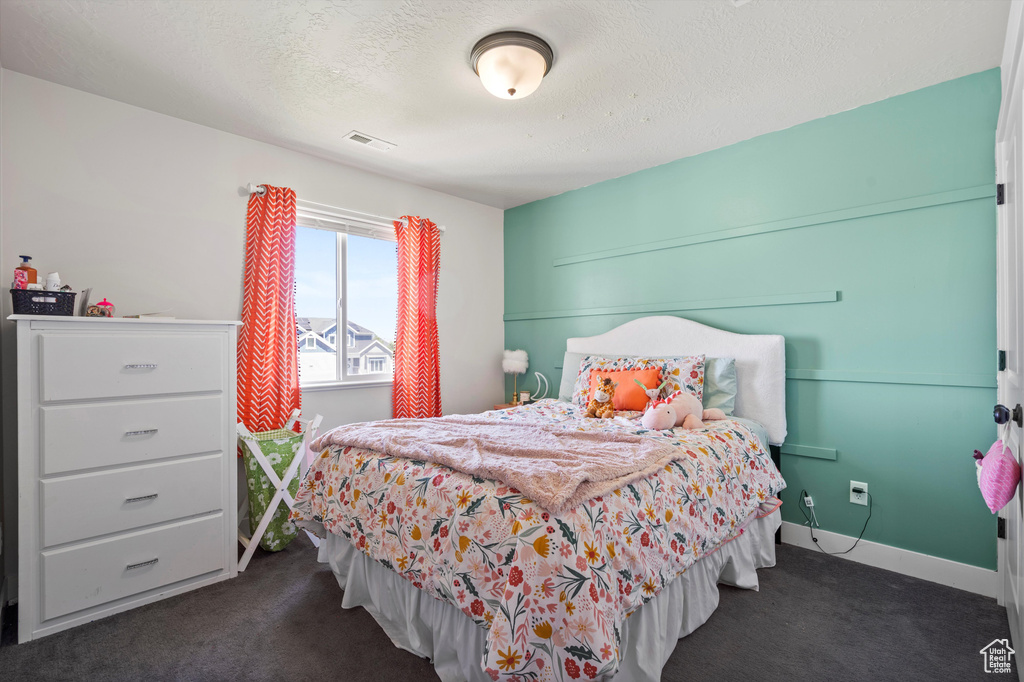 Bedroom featuring dark carpet and a textured ceiling