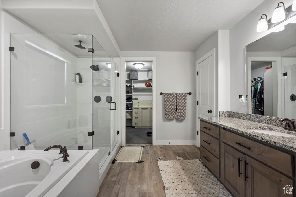 Bathroom featuring vanity, hardwood / wood-style flooring, a textured ceiling, and plus walk in shower