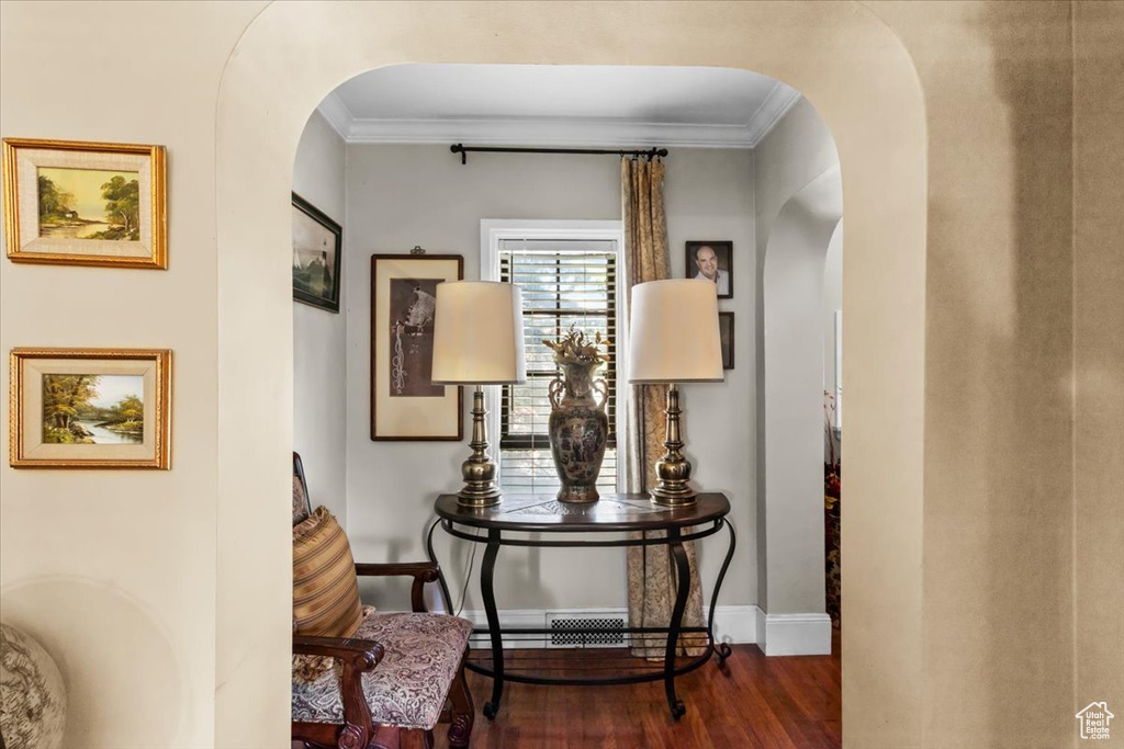 Sitting room with crown molding and dark wood-type flooring