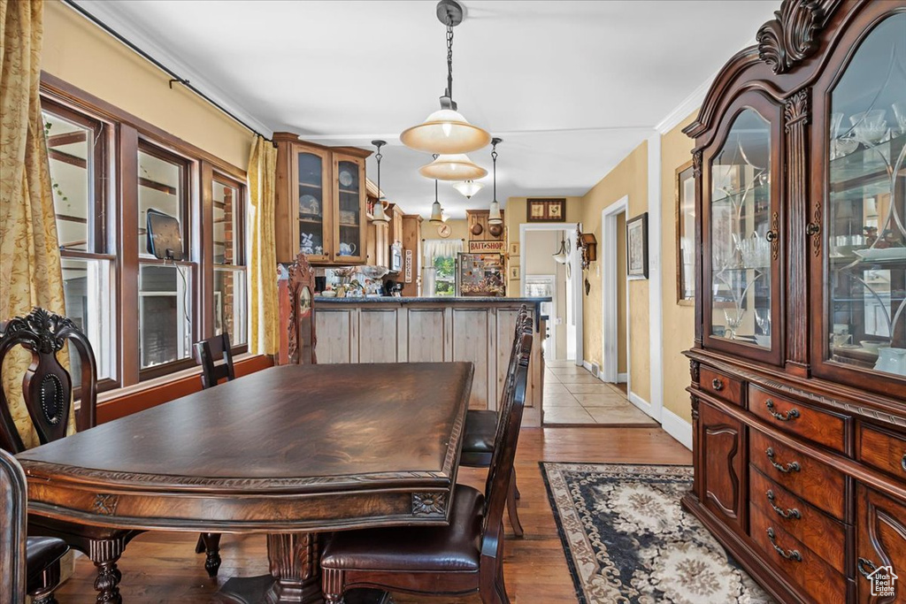 Dining area with ornamental molding and light hardwood / wood-style floors