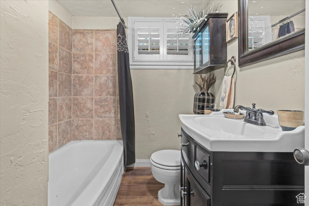 Full bathroom featuring shower / bath combination with curtain, large vanity, toilet, and wood-type flooring