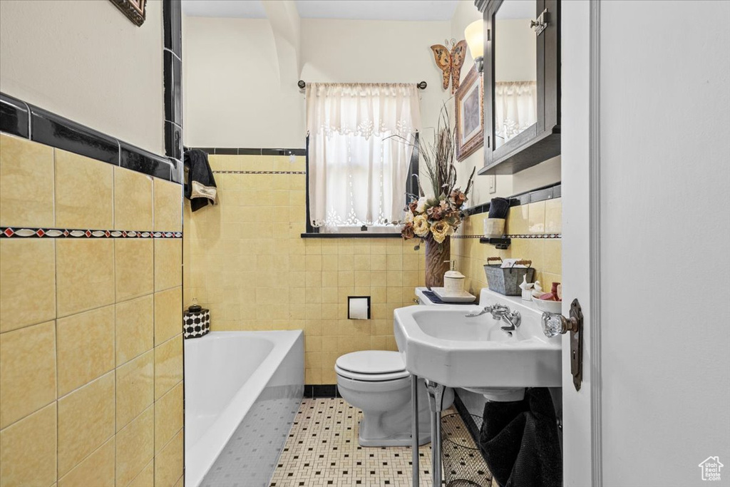 Bathroom featuring tile flooring, toilet, and tile walls