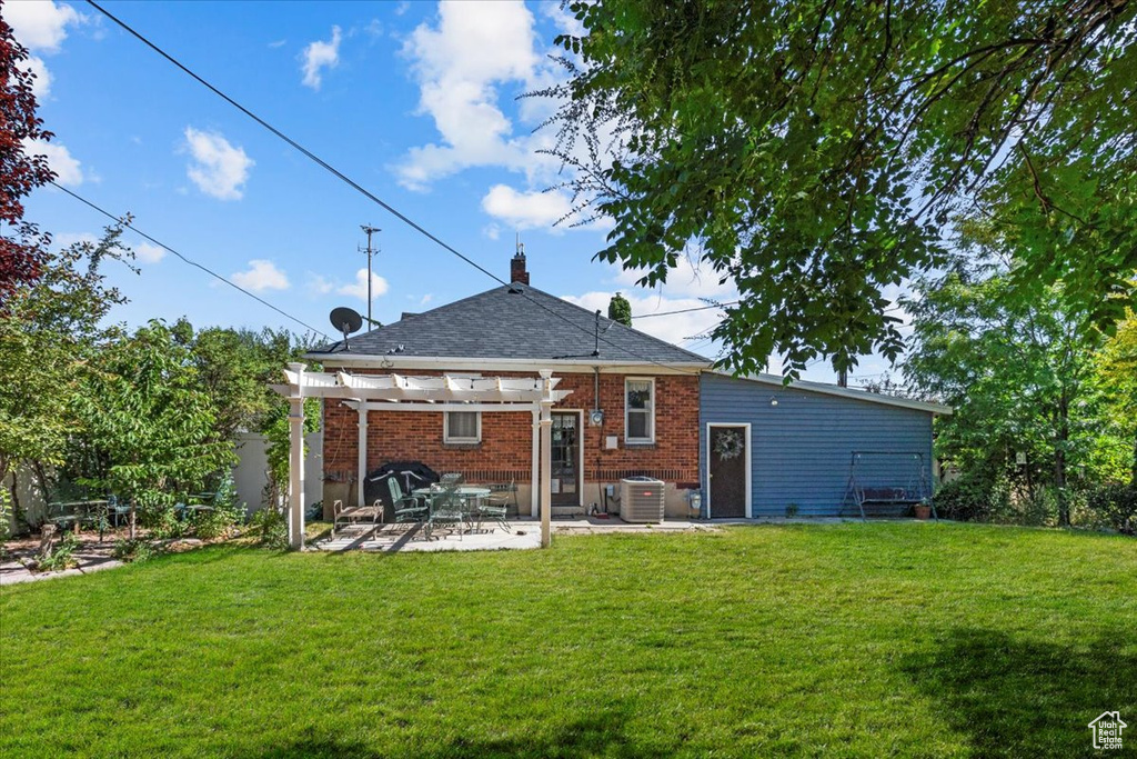 Rear view of house with a yard, a pergola, central AC unit, and a patio