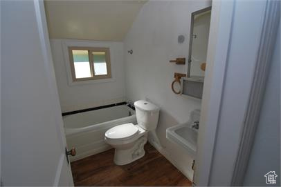 Bathroom featuring washtub / shower combination, hardwood / wood-style flooring, and toilet