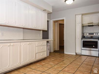 Kitchen with range, light tile flooring, and white cabinetry