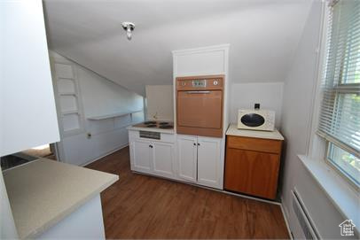 Kitchen featuring a wealth of natural light, white cabinetry, wall oven, and dark hardwood / wood-style floors