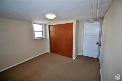 Unfurnished bedroom featuring a closet and dark colored carpet