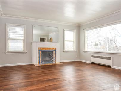 Unfurnished living room with radiator, ornamental molding, and dark hardwood / wood-style floors