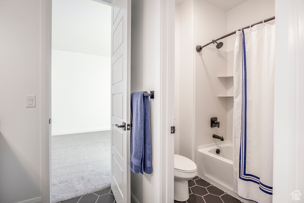 Bathroom featuring tile floors, shower / tub combo with curtain, and toilet