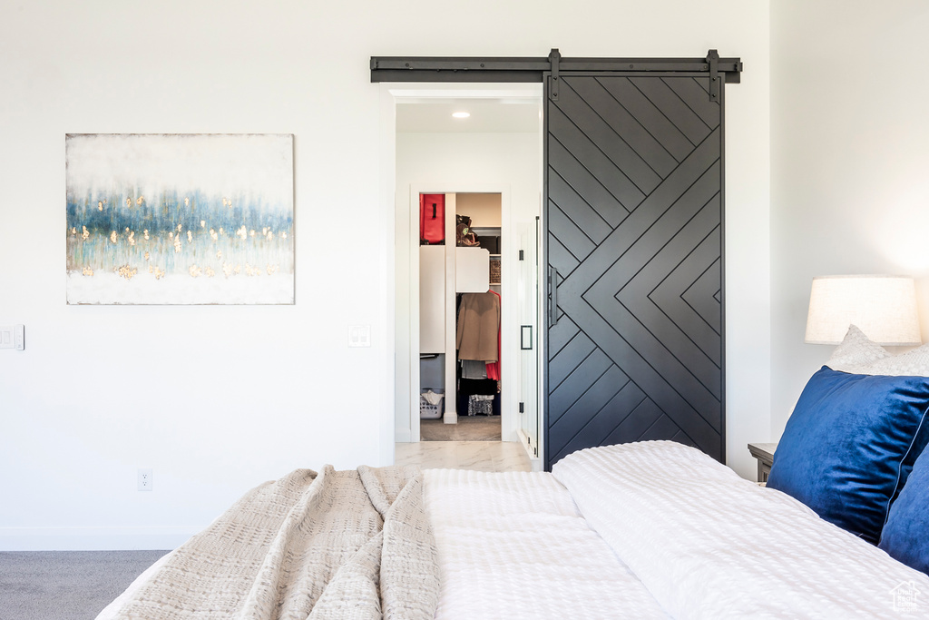 Bedroom with a barn door and carpet flooring