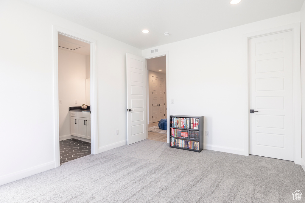 Bedroom featuring light colored carpet and ensuite bath