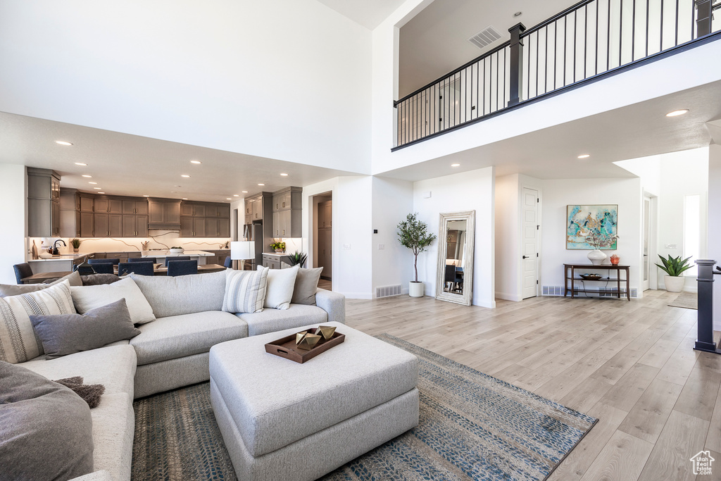 Living room with a high ceiling, sink, and light wood-type flooring