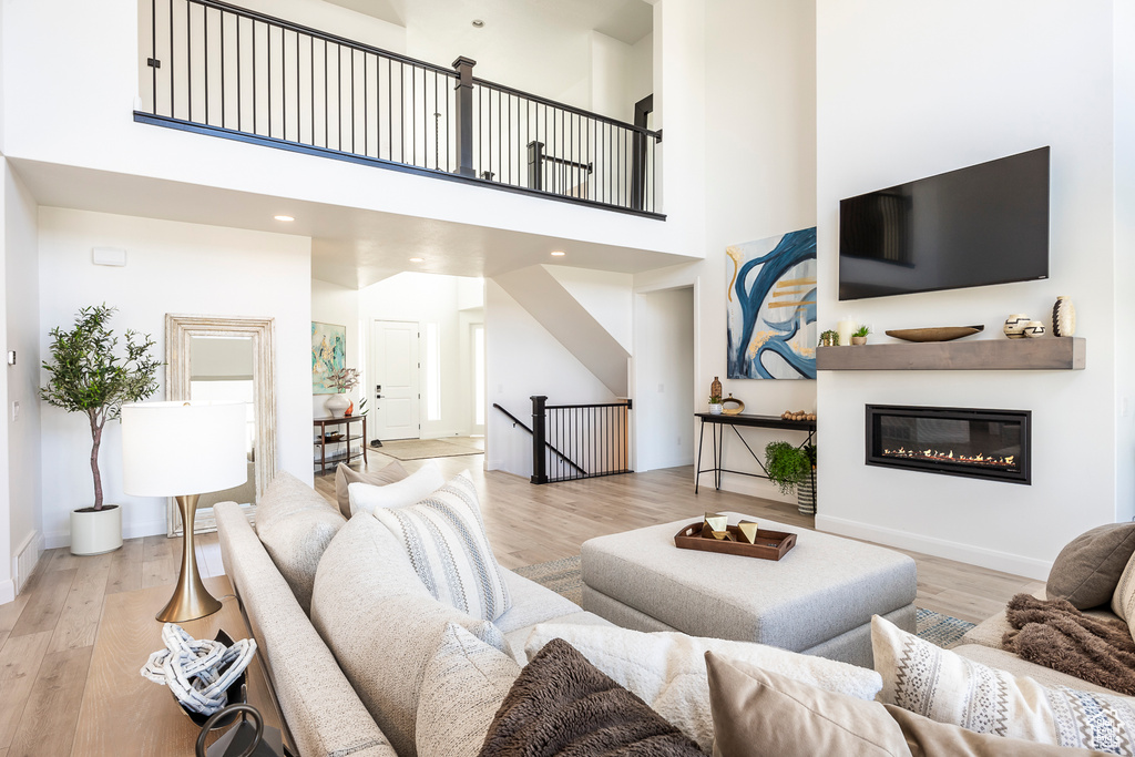 Living room with light hardwood / wood-style floors and a high ceiling