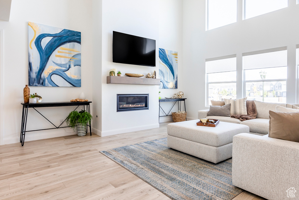 Living room with a towering ceiling and light hardwood / wood-style flooring