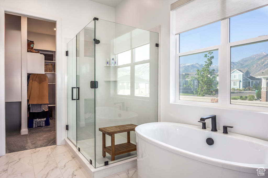 Bathroom with tile floors, a healthy amount of sunlight, and independent shower and bath