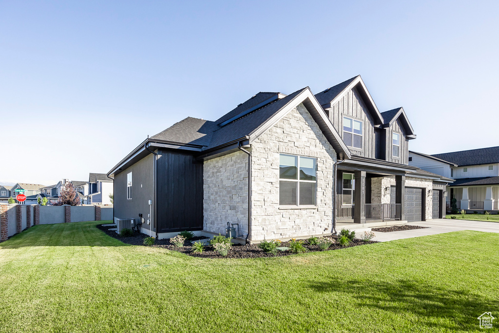 View of property exterior with a garage, a lawn, and central AC unit