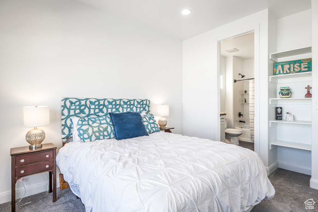 Bedroom featuring ensuite bathroom and dark carpet