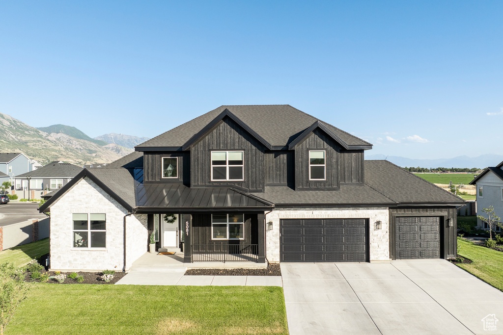 View of front of home with a front yard, a garage, and a mountain view