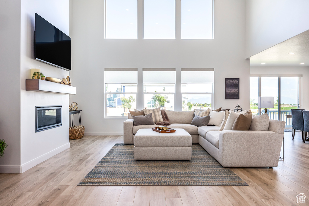 Living room featuring a high ceiling, plenty of natural light, and light wood-type flooring