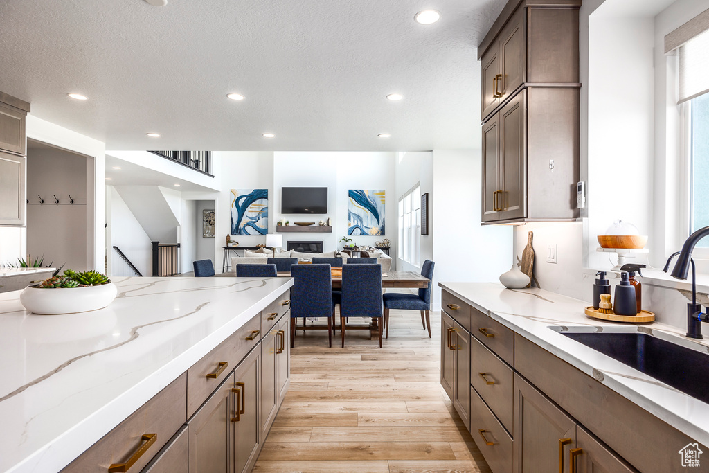 Kitchen featuring light stone countertops, sink, a textured ceiling, and light wood-type flooring