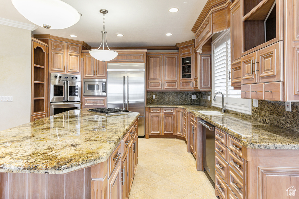 Kitchen featuring light stone countertops, built in appliances, backsplash, sink, and ornamental molding