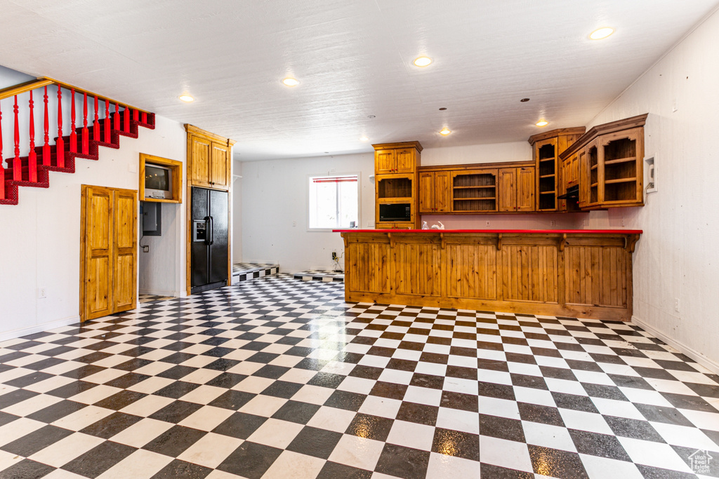 Kitchen featuring tile floors, kitchen peninsula, and black fridge with ice dispenser