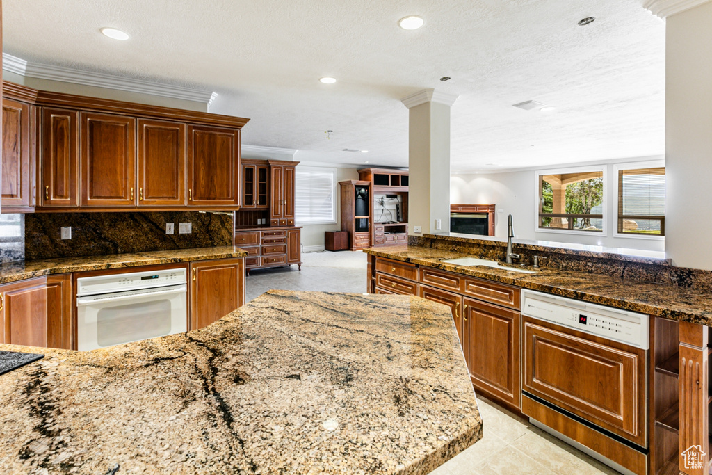 Kitchen featuring backsplash, ornamental molding, sink, white appliances, and light tile floors